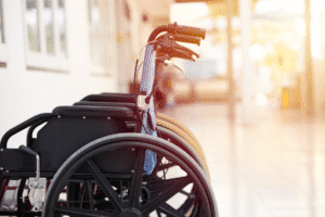 Row of empty wheelchairs in a nursing home hallway with sunlight in the background