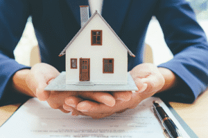 Hands holding a model house over property documents – Arizona community property law