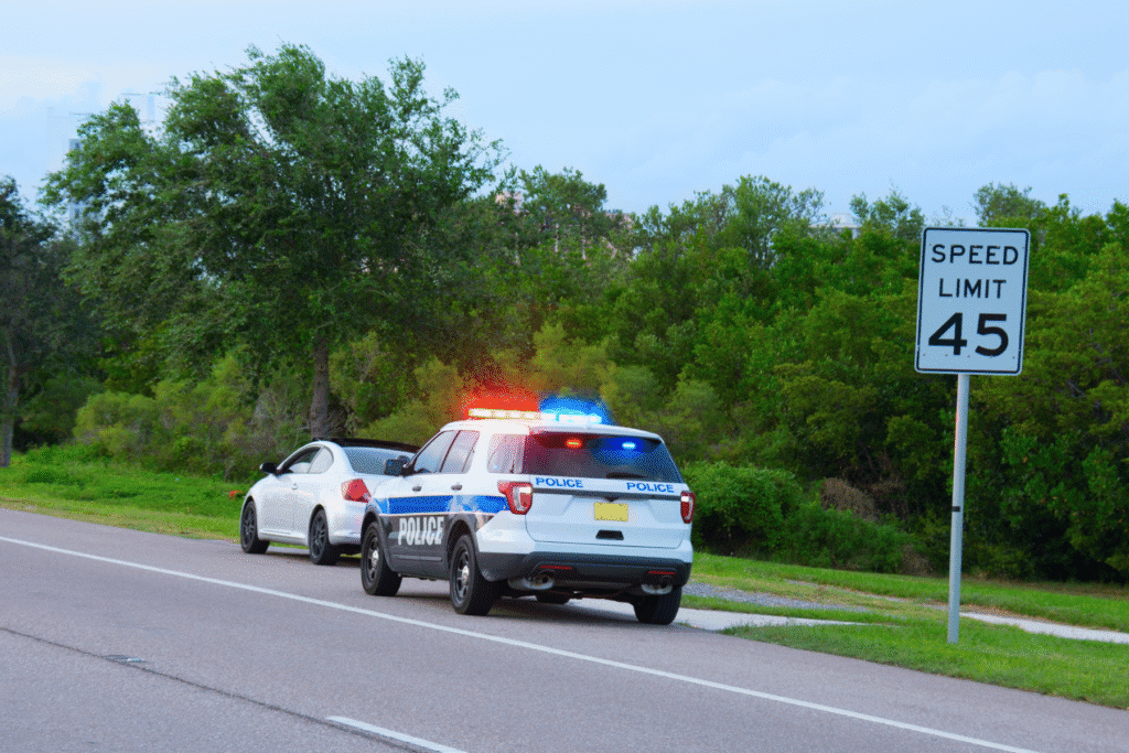 Police car with flashing lights pulls over driver on roadside in Scottsdale, Arizona during traffic stop.