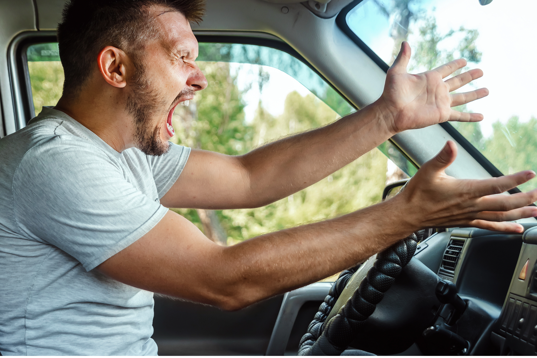 Man shouting and gesturing angrily while driving, representing road rage in Arizona.