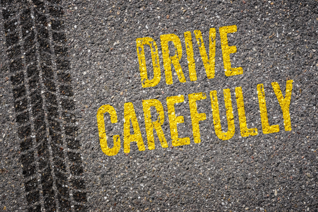 Drive carefully warning painted on asphalt next to tire skid marks – Arizona road safety image