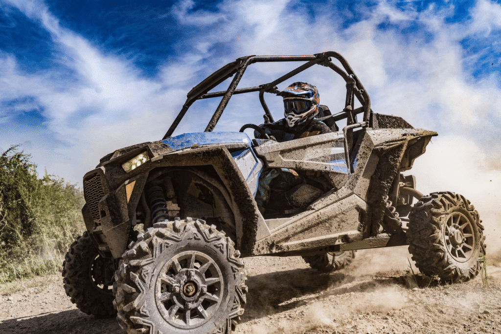 UTV driver riding through Arizona desert terrain kicking up dust under a bright blue sky